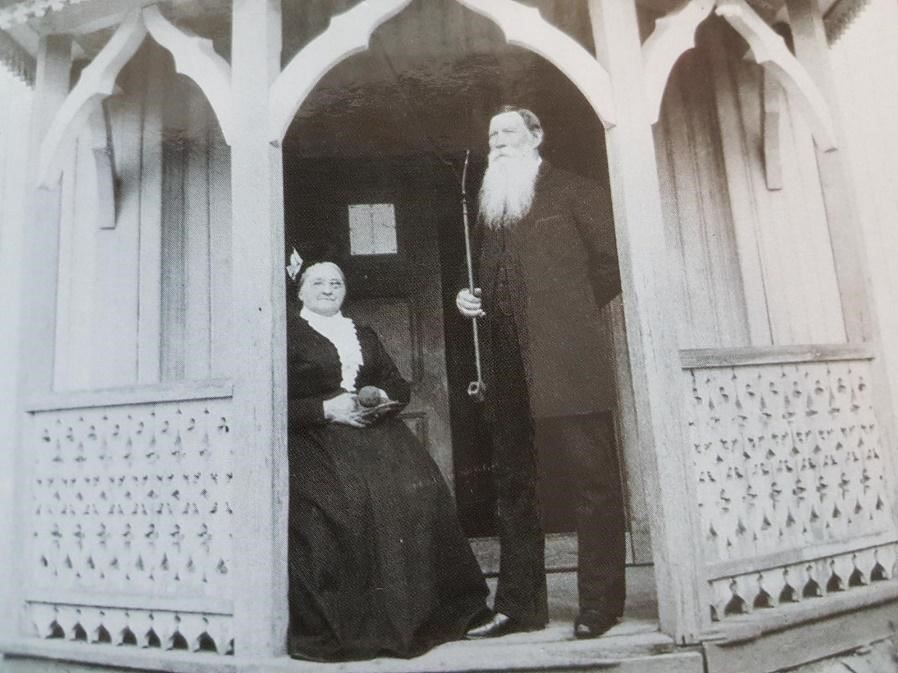 Patriarken, Martin Wettre, sammen med kona Karen, foran skolen sin, lett gjenkjennbar med sitt ruvende hvite skjegg og langpipa i hånda. Foto: Asker bibliotek